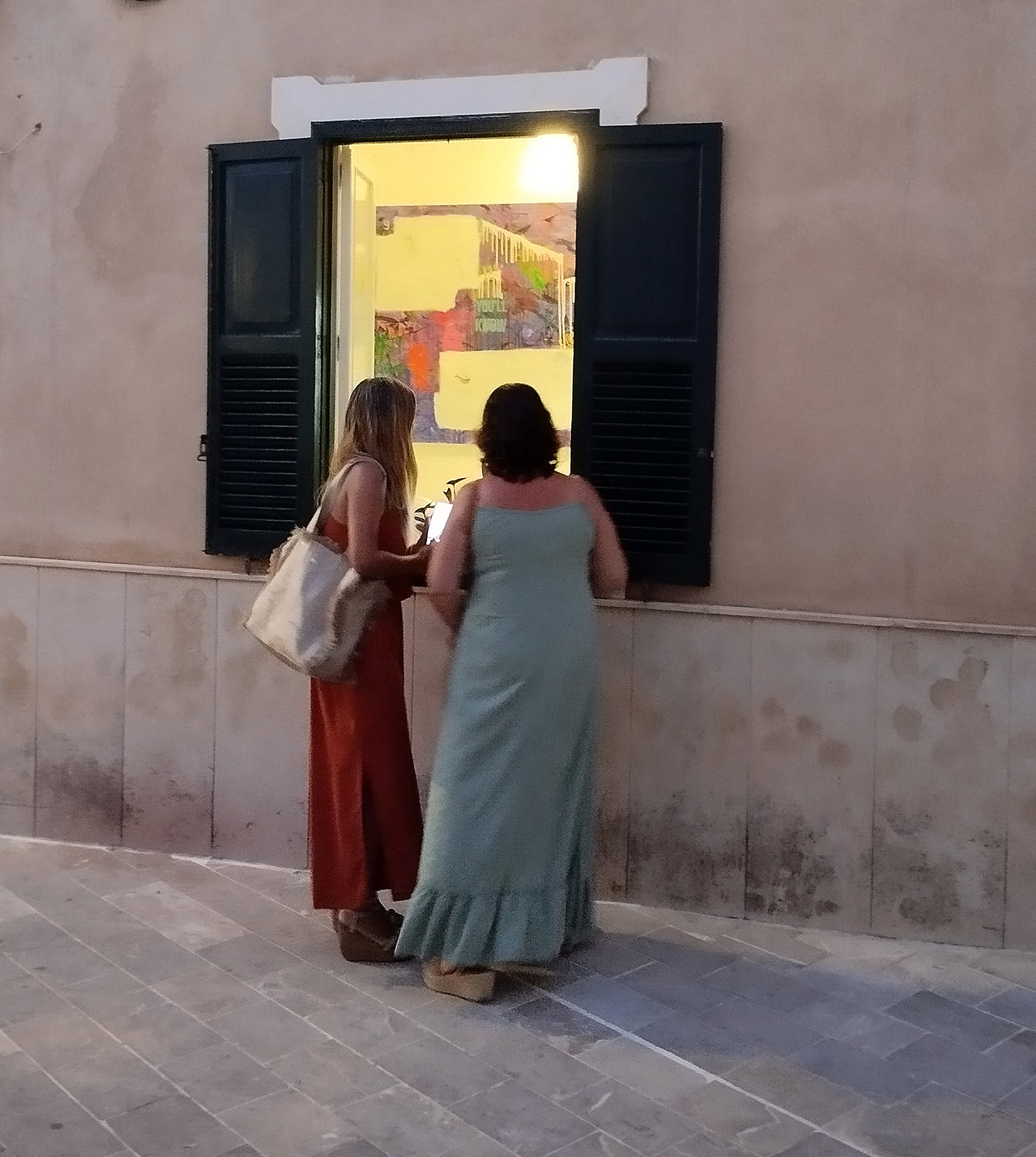 Gran Migjornale 2026. 2 women in front of the front window looking at a painting by Raphael Zelfa